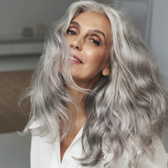 Model faces the camera with long, wavy, silvery grey hair. 