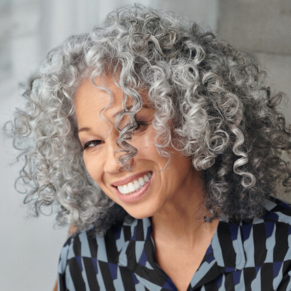 Model faces the camera with gray, curly hair.
