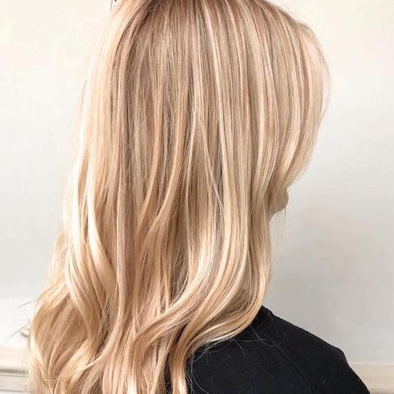 Side profile photo of woman with medium-length hair and sandy blonde highlights, created using Wella Professionals. 