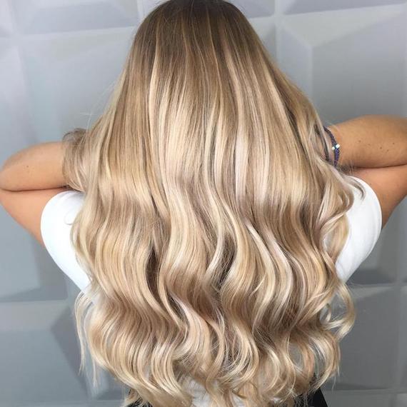 Foto von dem Hinterkopf einer Frau mit langem Haar und einer sandy-blonden Balayage, kreiert mit Wella Professionals. 