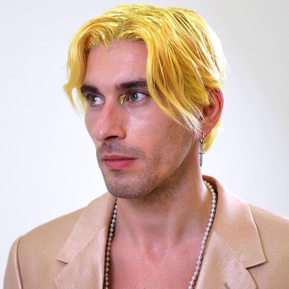 Model with short, center-parted, neon yellow hair looks away from the camera.