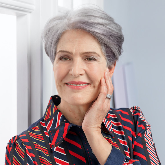 Woman with short, grey hair gazes off into the distance and smiles. 