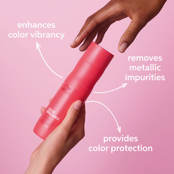 A bottle of INVIGO Brilliance Color Protection Shampoo is passed from one model’s hand to another’s. 