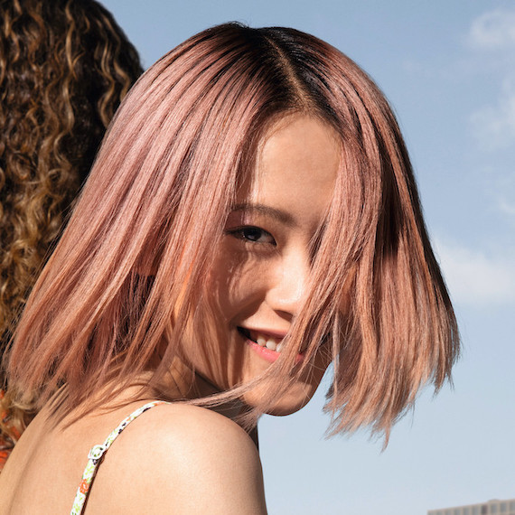Model facing the camera with a pastel pink bob haircut.