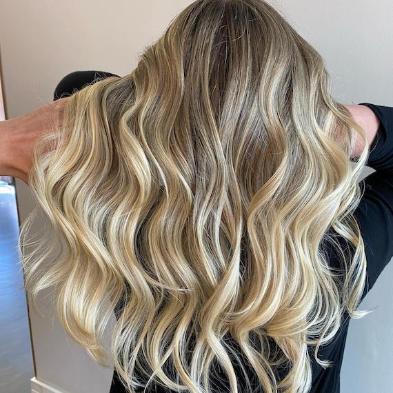 Back of woman’s head with long, wavy, blonde hair, created using Wella Professionals.  