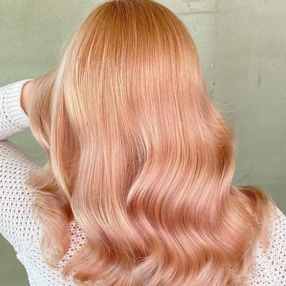 Back of woman’s head with mid-length, wavy, rose gold hair, created using Wella Professionals.  