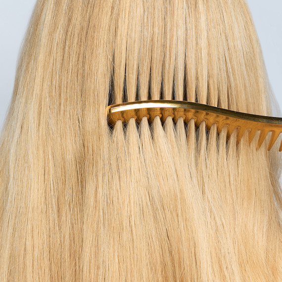 A model glides a comb through their smooth, blonde hair.