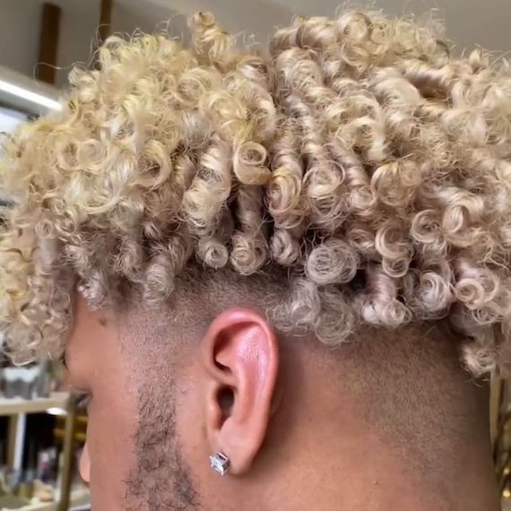 Back of model’s head featuring a shaved undercut and blonde curls.