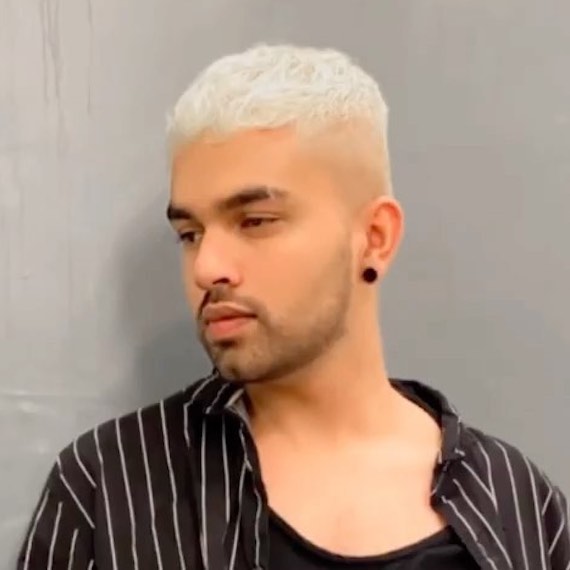Model with a platinum blonde buzz cut, featuring extra length on the top.
