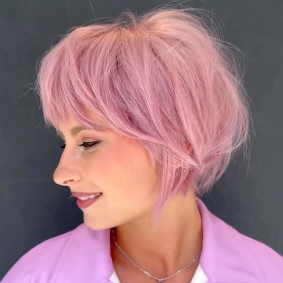 Side profile of model with pastel pink, layered bob haircut.