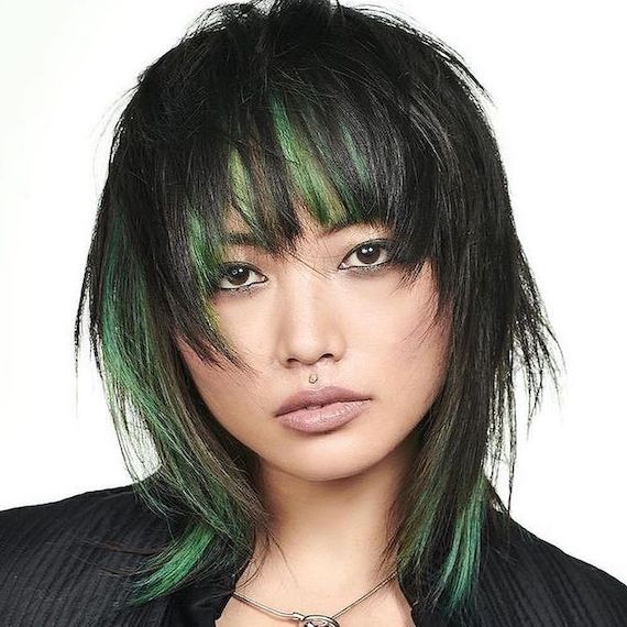 Model with black shag haircut, featuring green highlights.