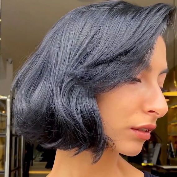 Side profile of model with a black, glossy bob and curtain bangs.