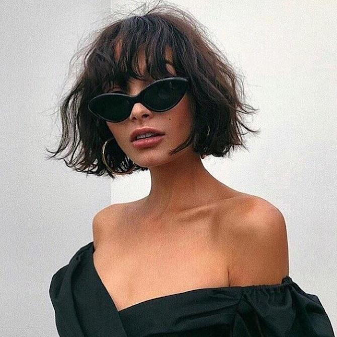 Photo of woman with sunglasses and brunette hair styled in a short, wavy bob with bangs, created using Wella Professionals