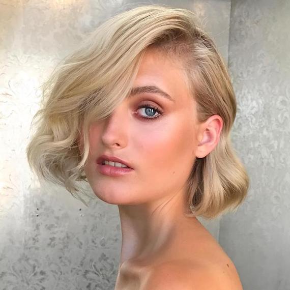 Photo of woman with blonde hair styled in a short, side-swept, wavy bob, created using Wella Professionals