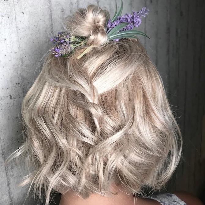 Photo of the back of a woman’s head with short, blonde, wavy hairstyle featuring floral details. Created using Wella Professionals 