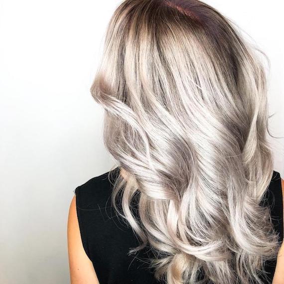 Back of woman’s head with long, wavy, silver balayage hair, created using Wella Professionals. 