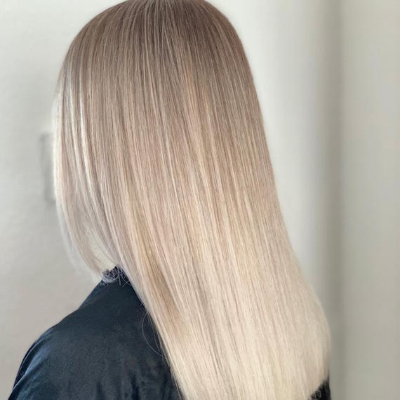 Side profile of woman with super-straight, ice blonde sombre hair, created using Wella Professionals.