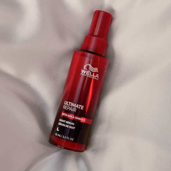ULTIMATE REPAIR Night Serum bottle on silk sheets.