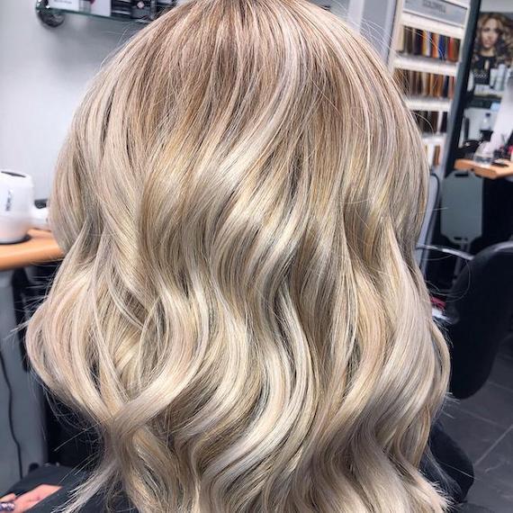 Back of woman’s head with loosely curled, stone blonde hair, created using Wella Professionals. 