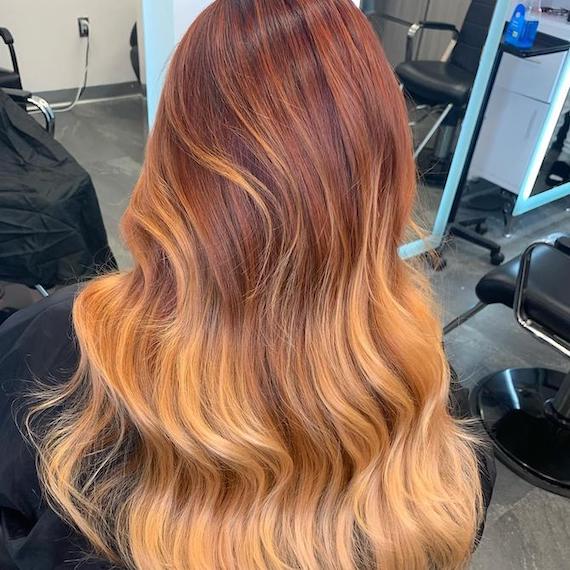 Back of woman’s head with long, wavy, ginger peach hair, created using Wella Professionals. 