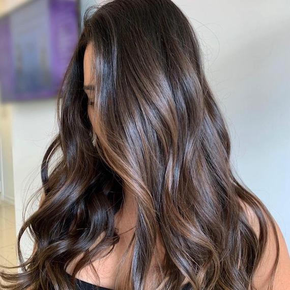 Woman with long, brunette hair and brown balayage, created using Wella Professionals. 