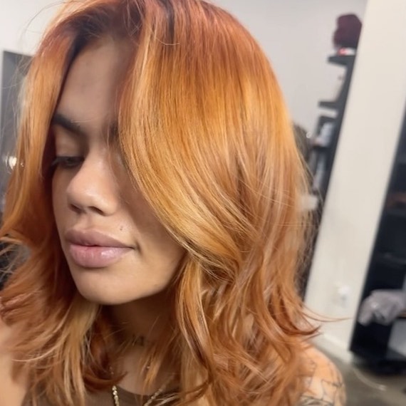 Model with glossy, blow-dried, strawberry blonde hair featuring hints of bronze.