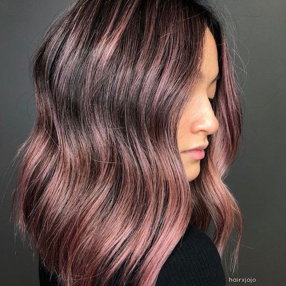 Side profile of model with mid-length brown hair and strawberry highlights.