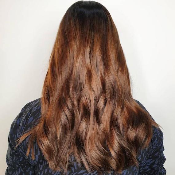 Model with long, brown, wavy hair and subtle highlights, created using Wella Professionals. 