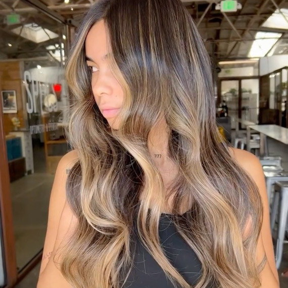 Side profile of model with brown hair and toffee balayage.