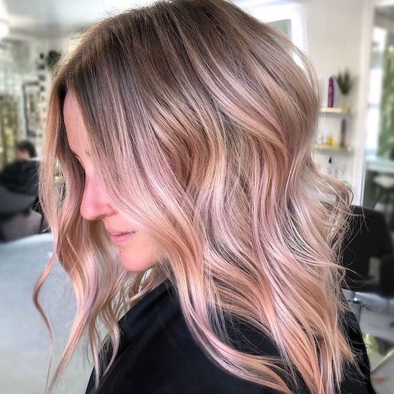 Side profile of model with blonde hair and pastel pink balayage.