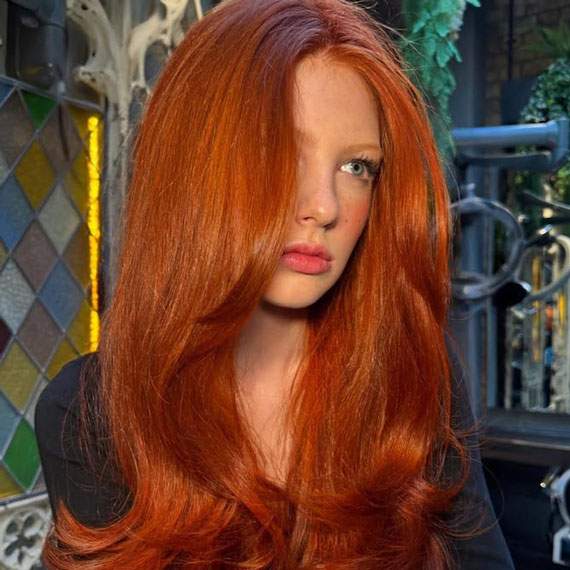 Model with bright ginger hair styled in a glossy blow-dry.