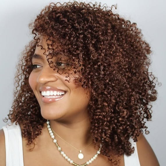 Model with super-glossy, dark brown, curly hair.