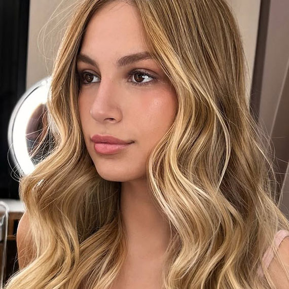 Model with long, ultra-glossy, honey blonde hair styled in loose waves.