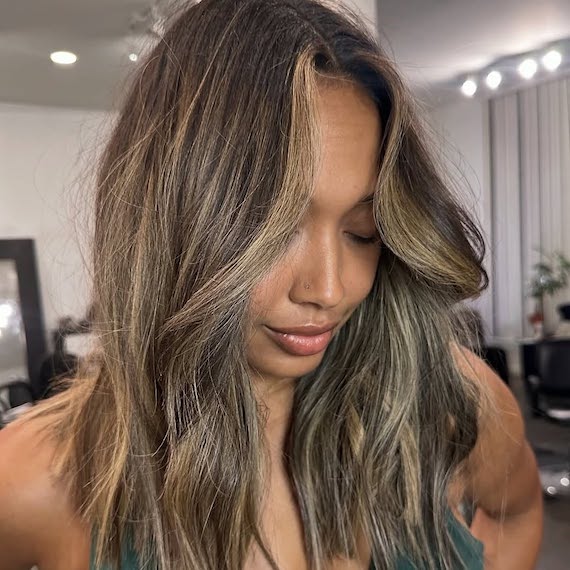 Model with loosely tousled, dark brown hair featuring caramel highlights.