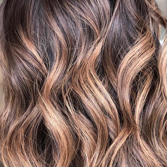 Close-up image of balayage hair color, styled in loose curls, created by Wella Professionals.