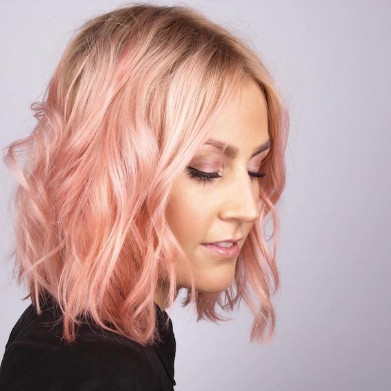 Side profile of a woman with a peach, wavy bob, styled using Wella Professionals