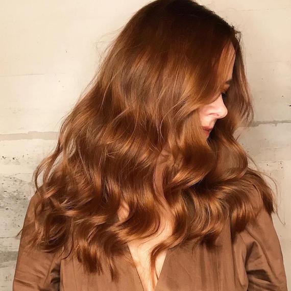 Side profile of a woman with loose wavy hair, styled using Wella Professionals