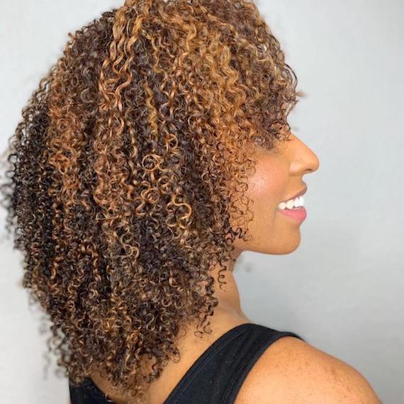 Side profile of a woman with defined curly hair, styled using Wella Professionals