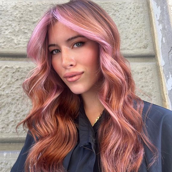 Model with long, wavy, strawberry blonde hair featuring a pastel pink face frame.