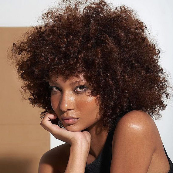 Model with long, full, dark brown, curly hair that glows with health. 