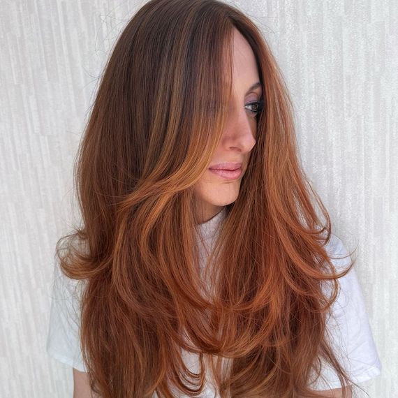 Model with long, blow-dried, copper hair featuring long layers.
