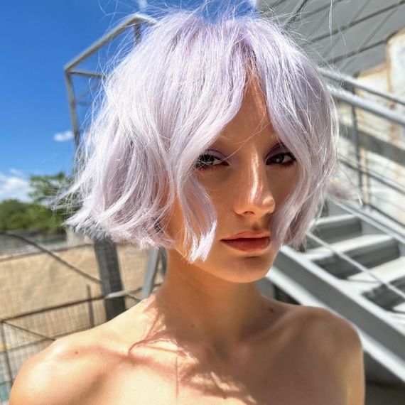 Model on a sunny rooftop, with short, lilac frost colored hair.