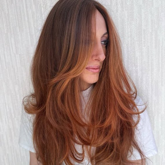 Model with long, auburn hair and strawberry blonde balayage.