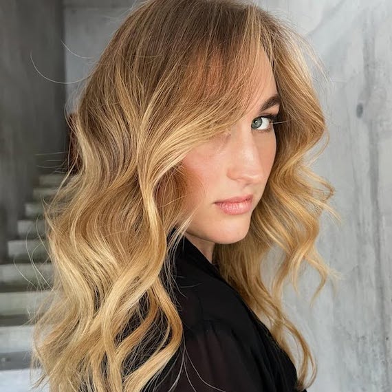 Model with long, dark blonde hair featuring golden balayage.