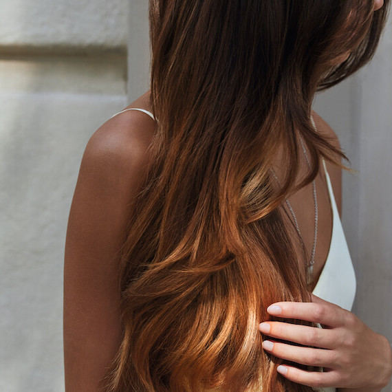 Side of model’s head with long, dark brown hair. 