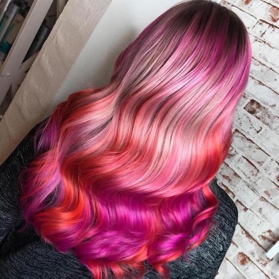 Back of woman’s head with pink and orange sunset hair, created using Wella Professionals.