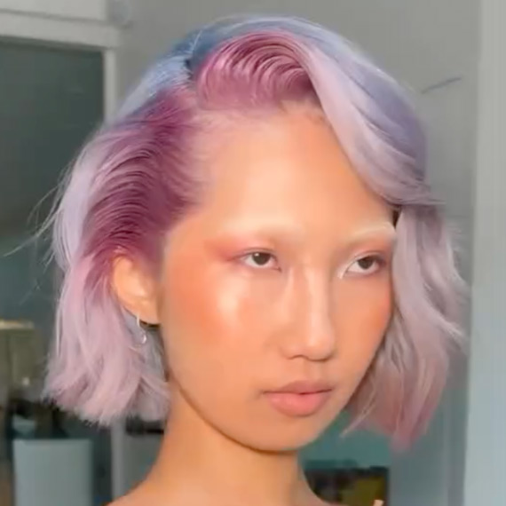 Model with chin-length, platinum blonde bob featuring pink and blue highlights.