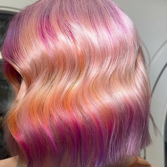 Model with shoulder-length, blonde hair featuring hints of bright pink, purple, orange and gold.