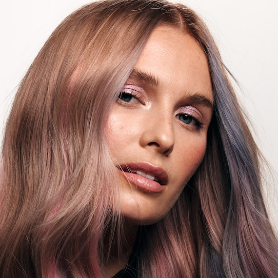 Model with dark blonde hair featuring strokes of pastel pink, blue and purple tones.