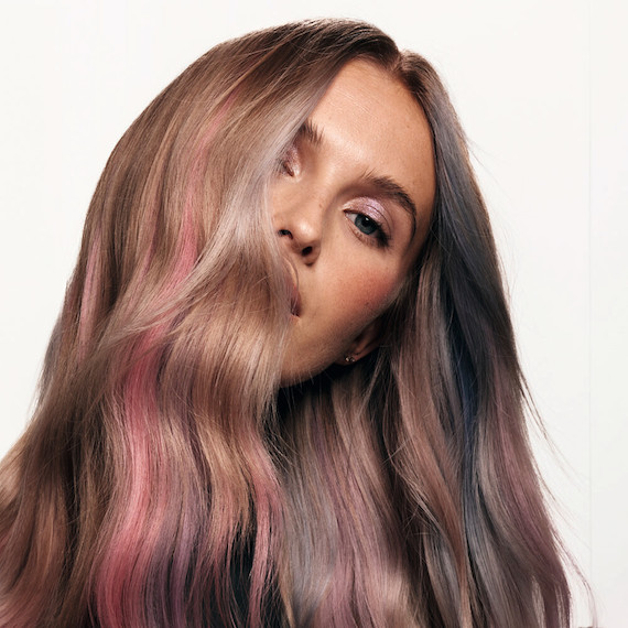 Model with dark blonde hair featuring strokes of pastel pink, blue and purple tones.